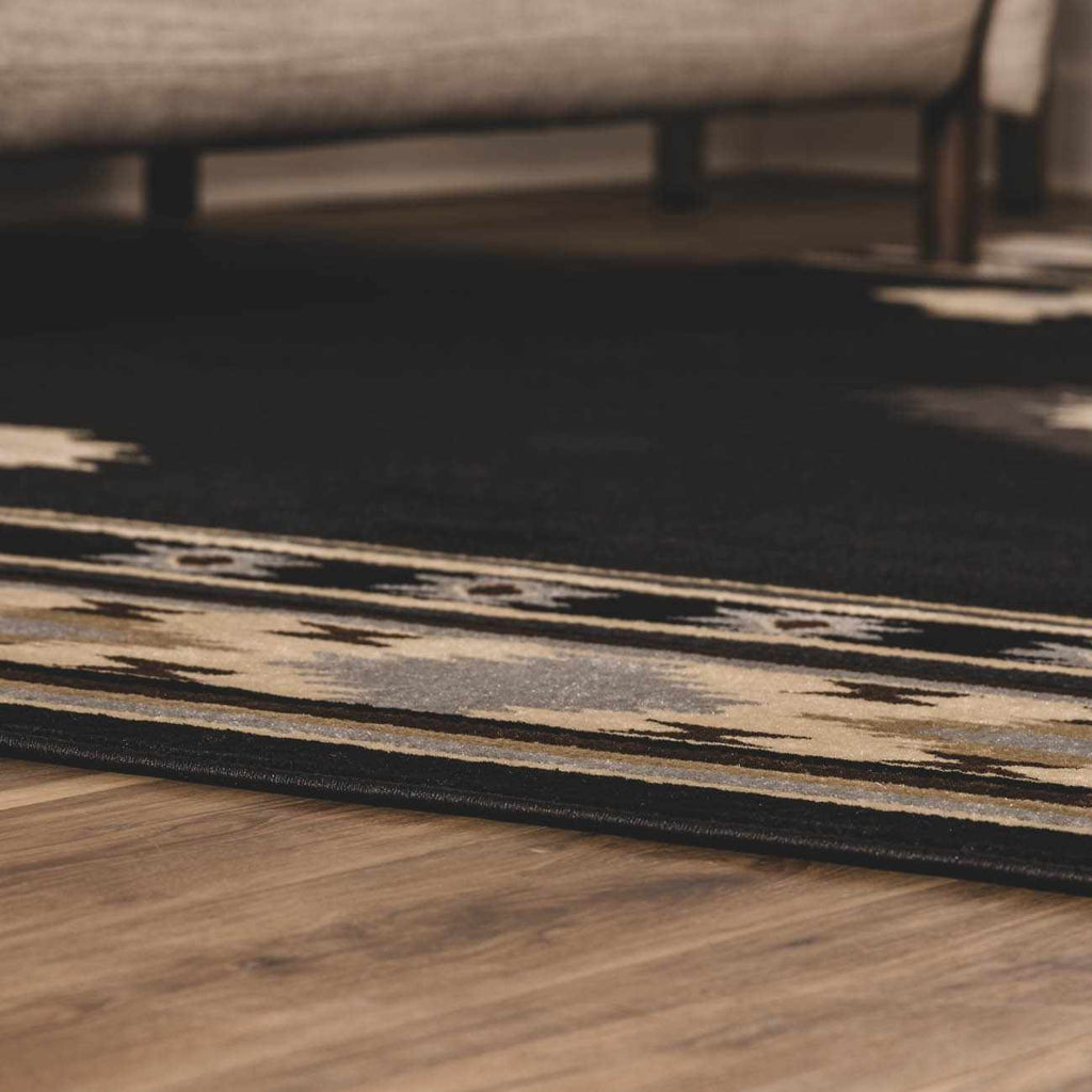 Close-up of a patterned rug on a wooden floor with a blurred background
