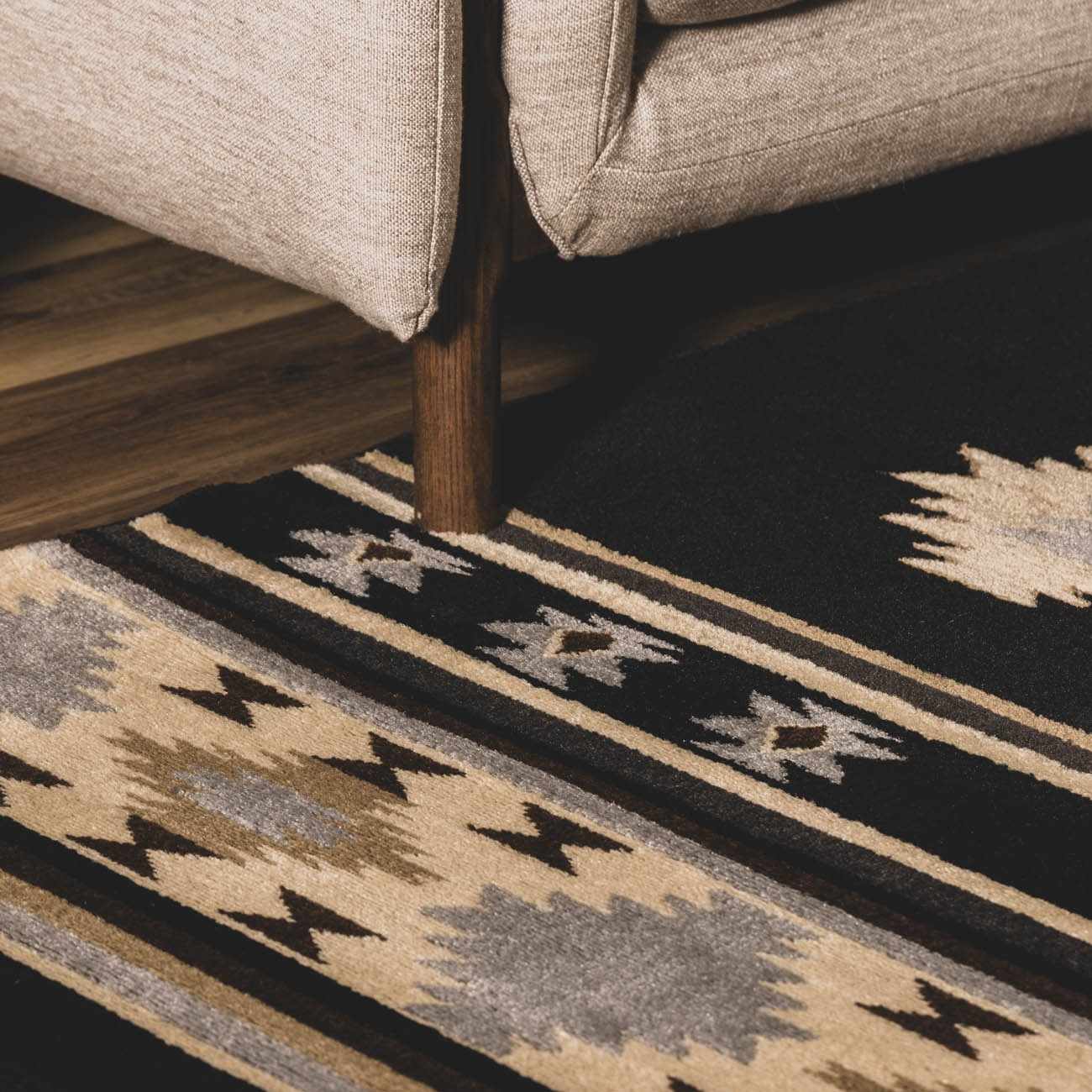 Patterned rug with geometric design in front of a beige sofa