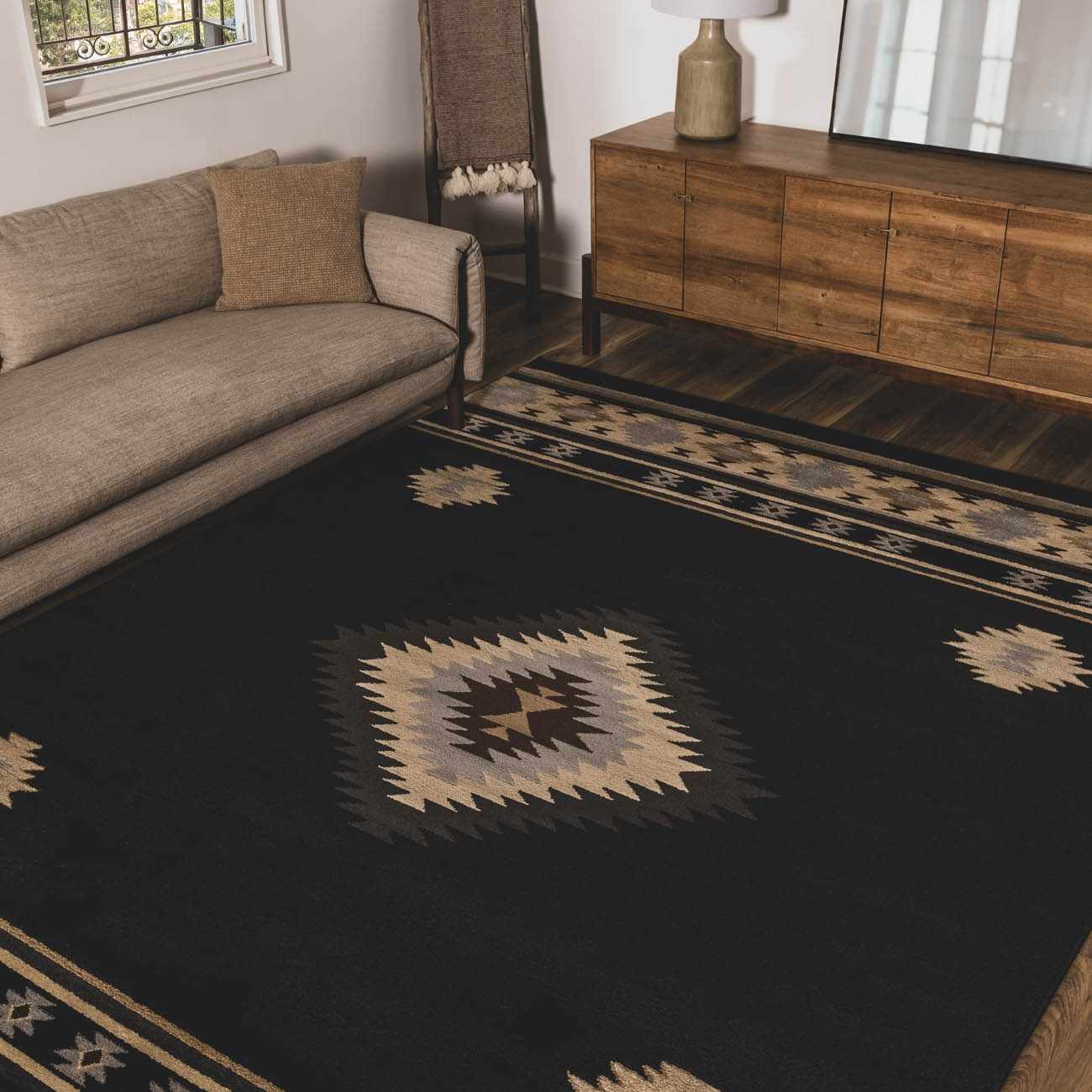 Living room with a black patterned rug, gray sofa, wooden sideboard, and chair.
