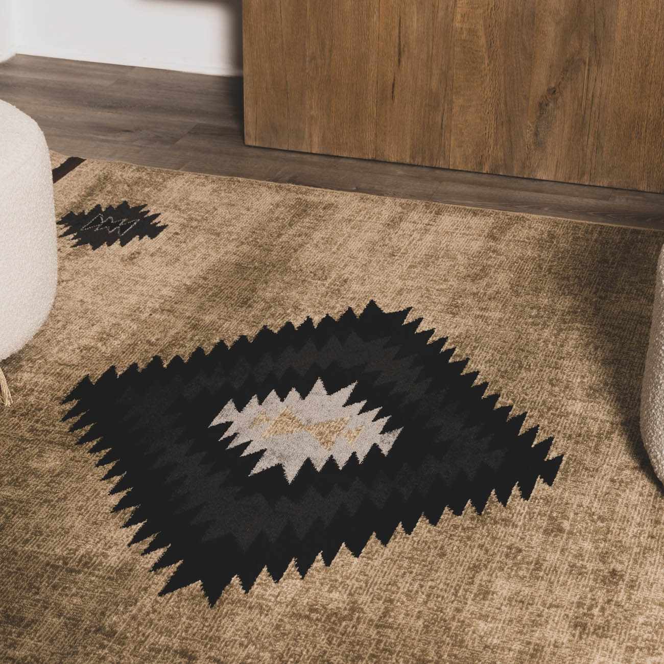 Brown rug with black and white geometric pattern on a wooden floor.
