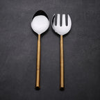 Two spoons with golden handles on a dark gray background