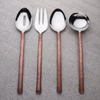 Set of four silver cutlery items with brown handles on a gray surface