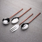 Set of silver cutlery with copper handles on a gray surface