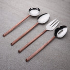 Set of silver cutlery with copper handles on a gray surface