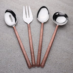 Set of four copper-handled silverware on a gray surface