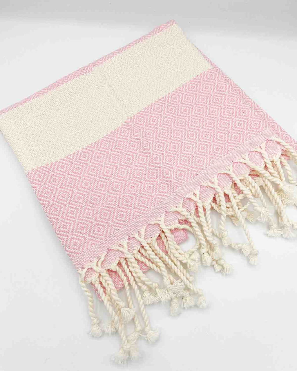 Pink diamond patterned hand towel with cream tassels on a white background