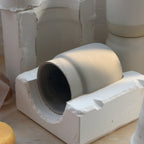 Ceramic mold with a cylindrical object inside on a wooden surface