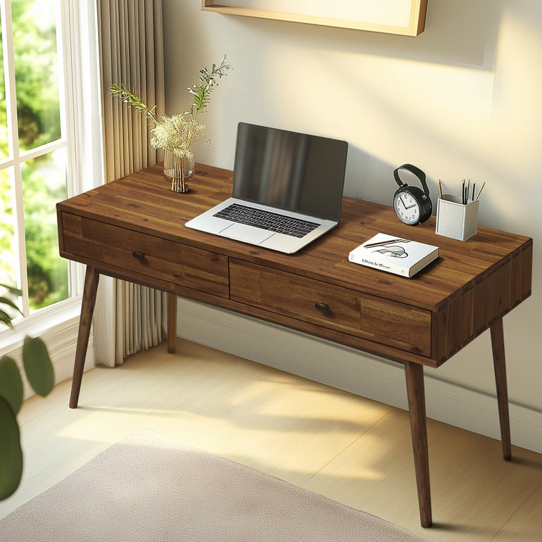 Wooden desk with laptop, notebook, and clock in a bright room