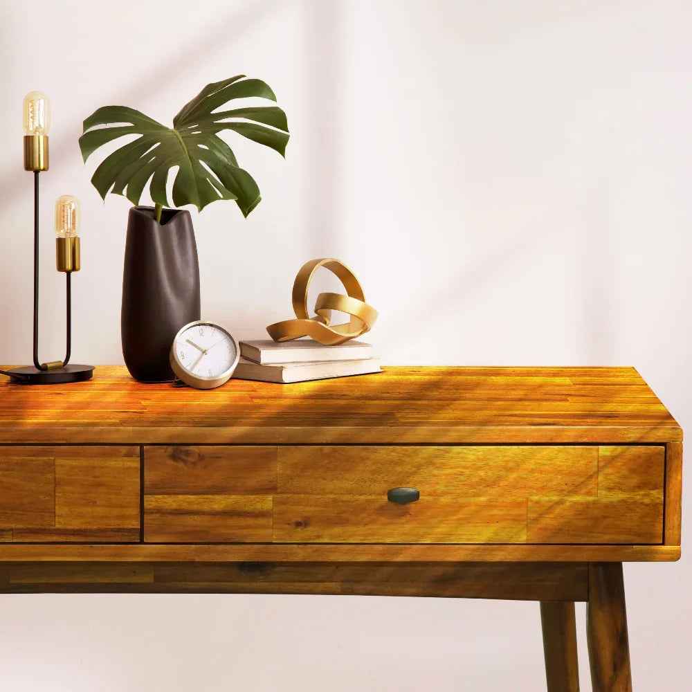 Wooden console table with decorative items including a plant, clock, and books on a white background