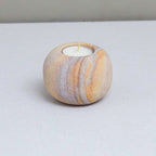 Marble-patterned candle holder with a candle on a gray surface