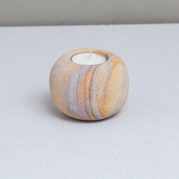 Marble-patterned candle holder with a candle on a gray surface