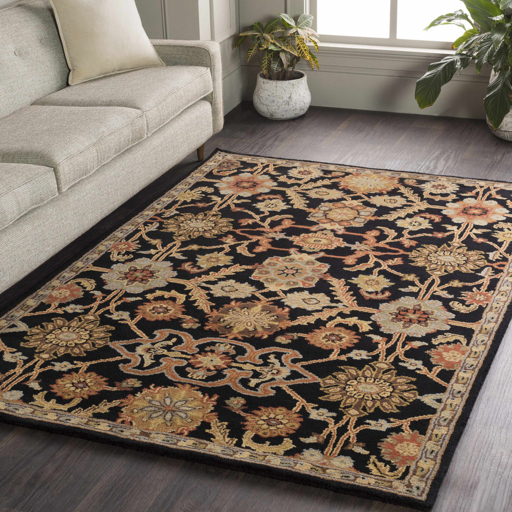 Decorative floral rug on a wooden floor with a couch and plants in the background