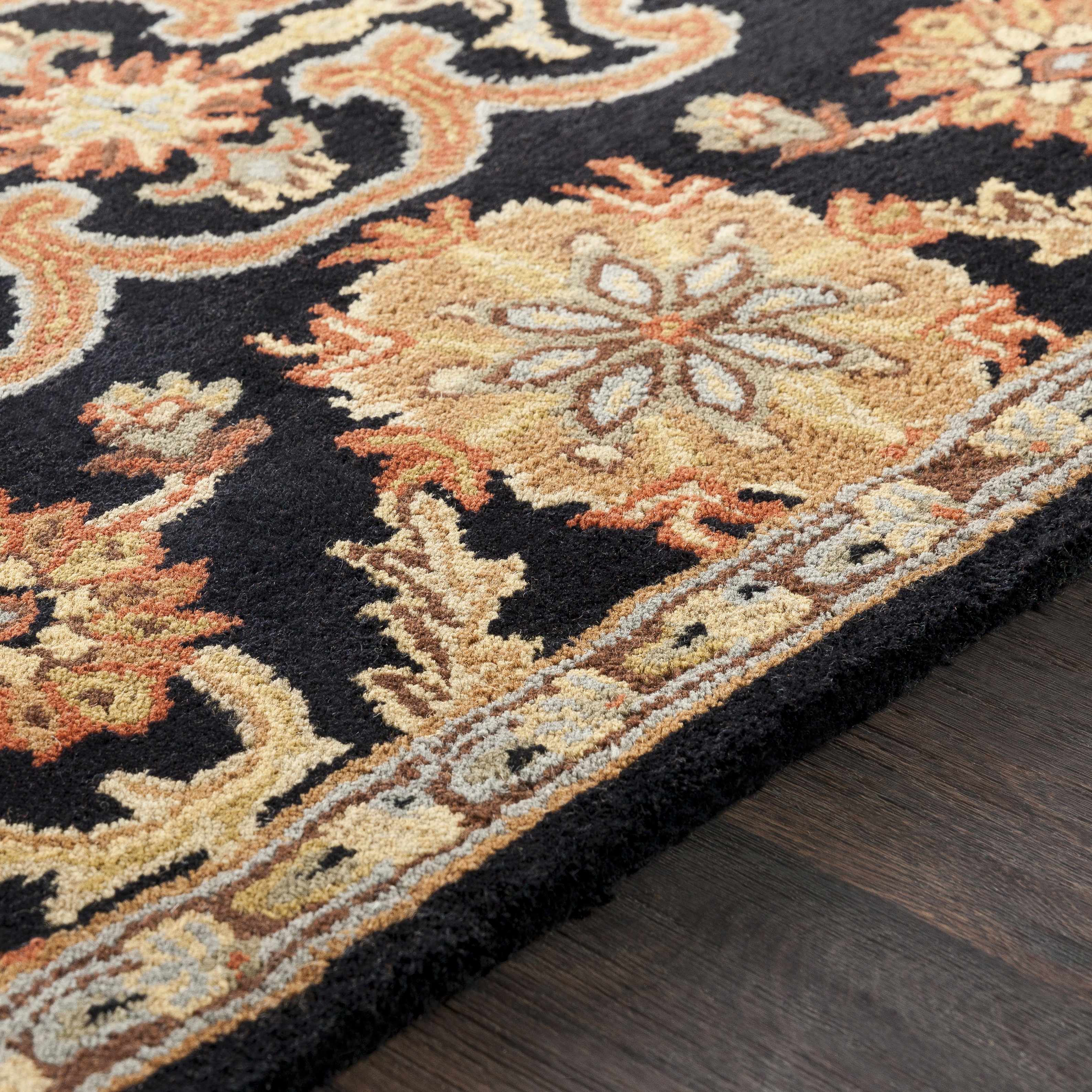 Close-up of an ornate rug with floral patterns on a wooden floor.