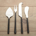 Set of four black-handled silver utensils on a white background