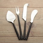 Set of four metal cheese tools with black handles on a wooden surface