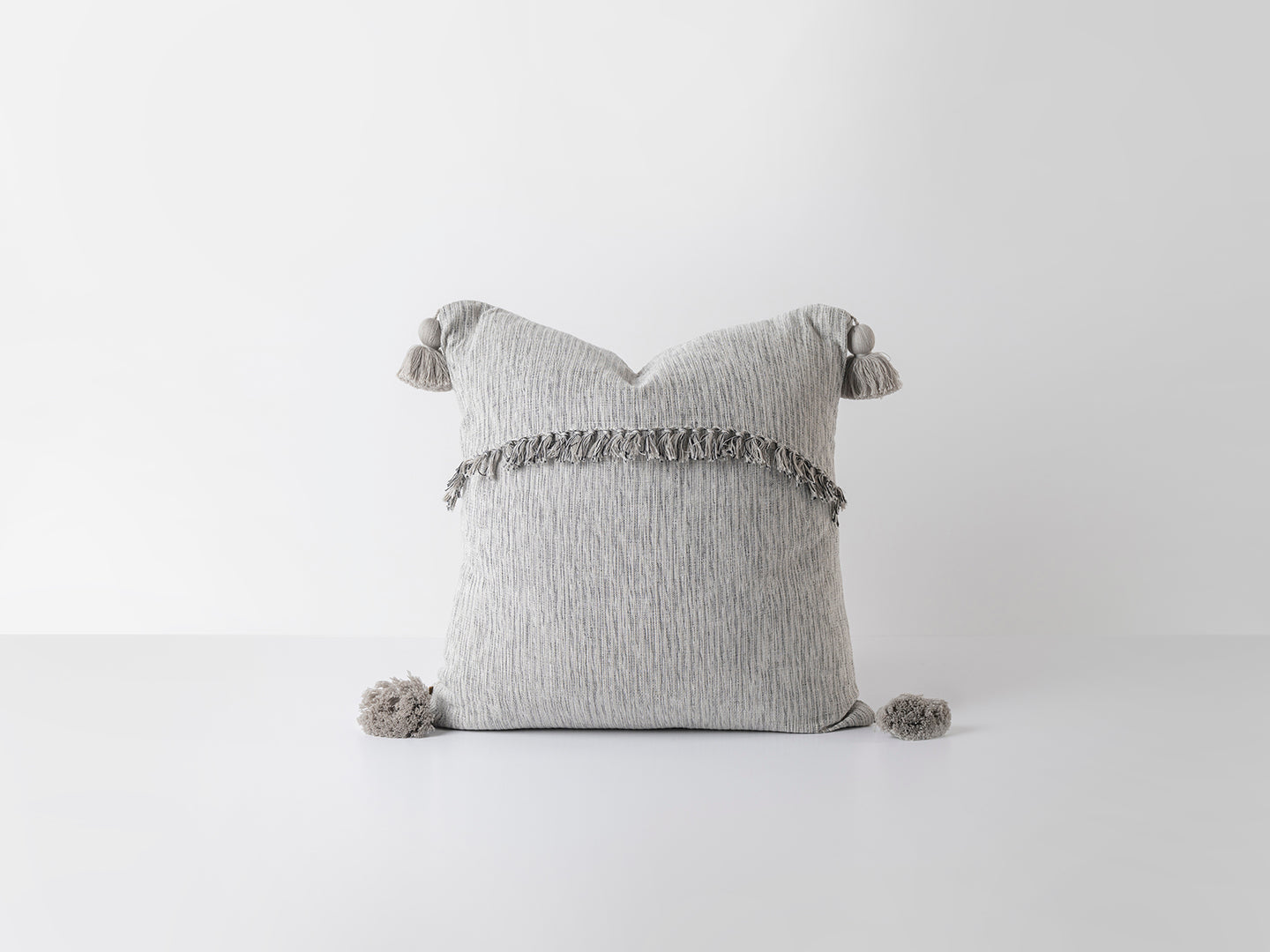 Gray pillow with tassels on a white background