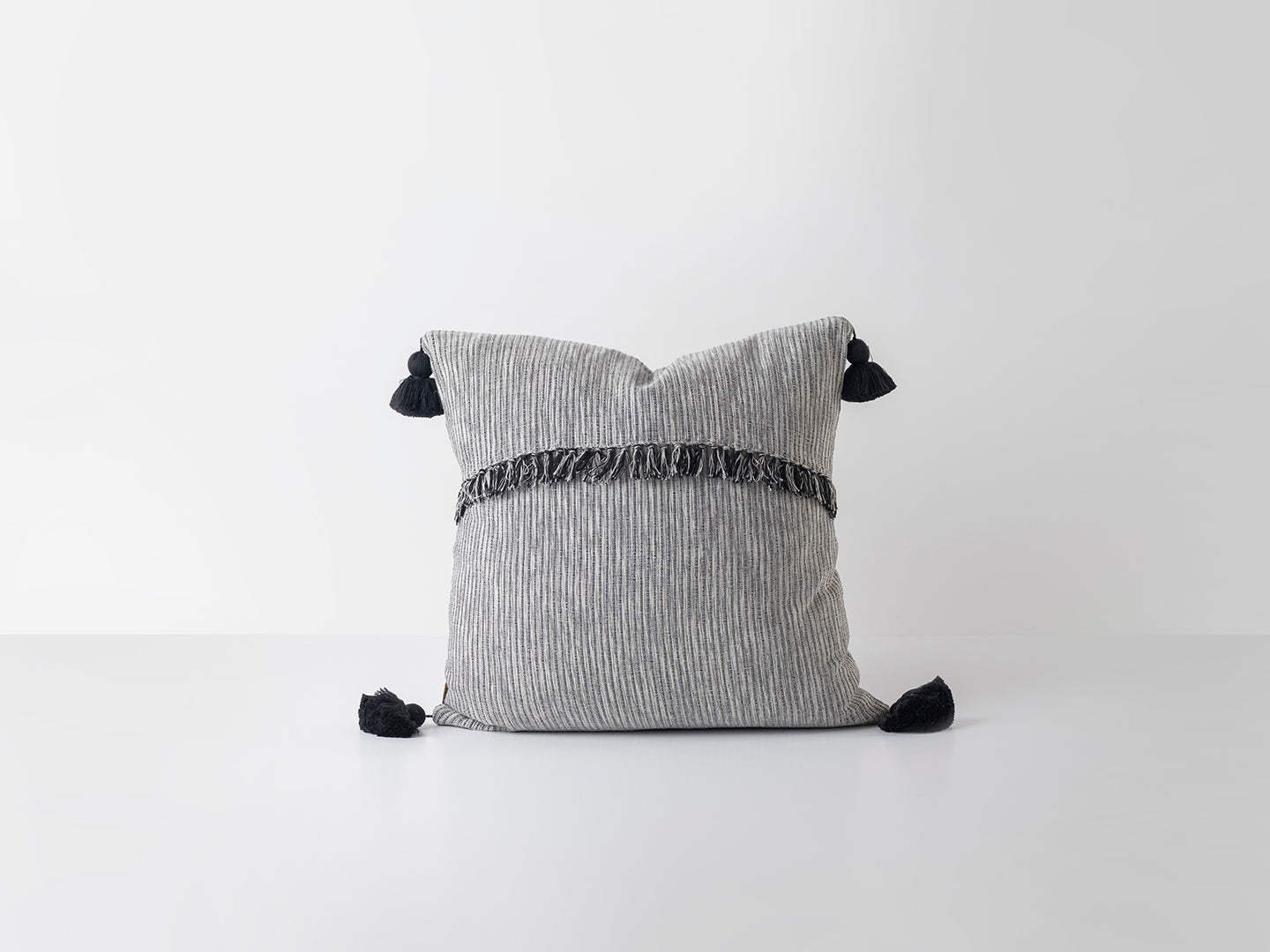 Gray pillow with black tassels on a white background