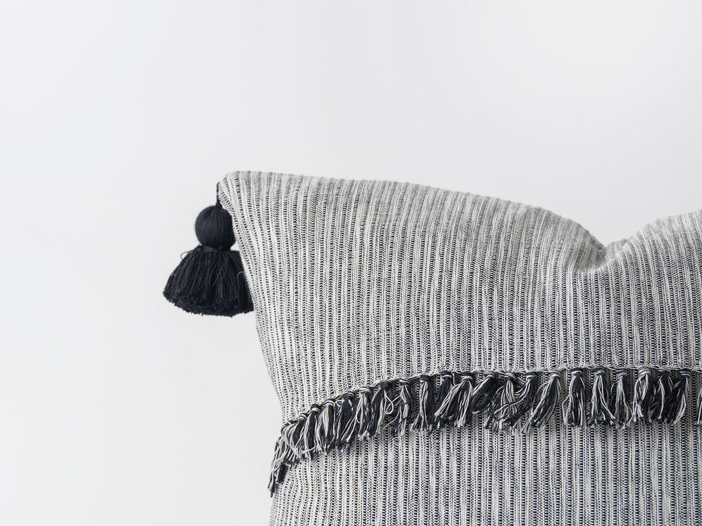 Textured pillow with tassels on a light gray background