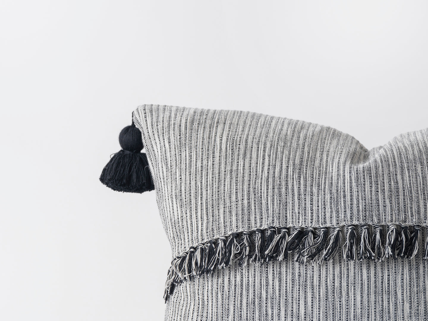 Textured pillow with tassels on a light gray background