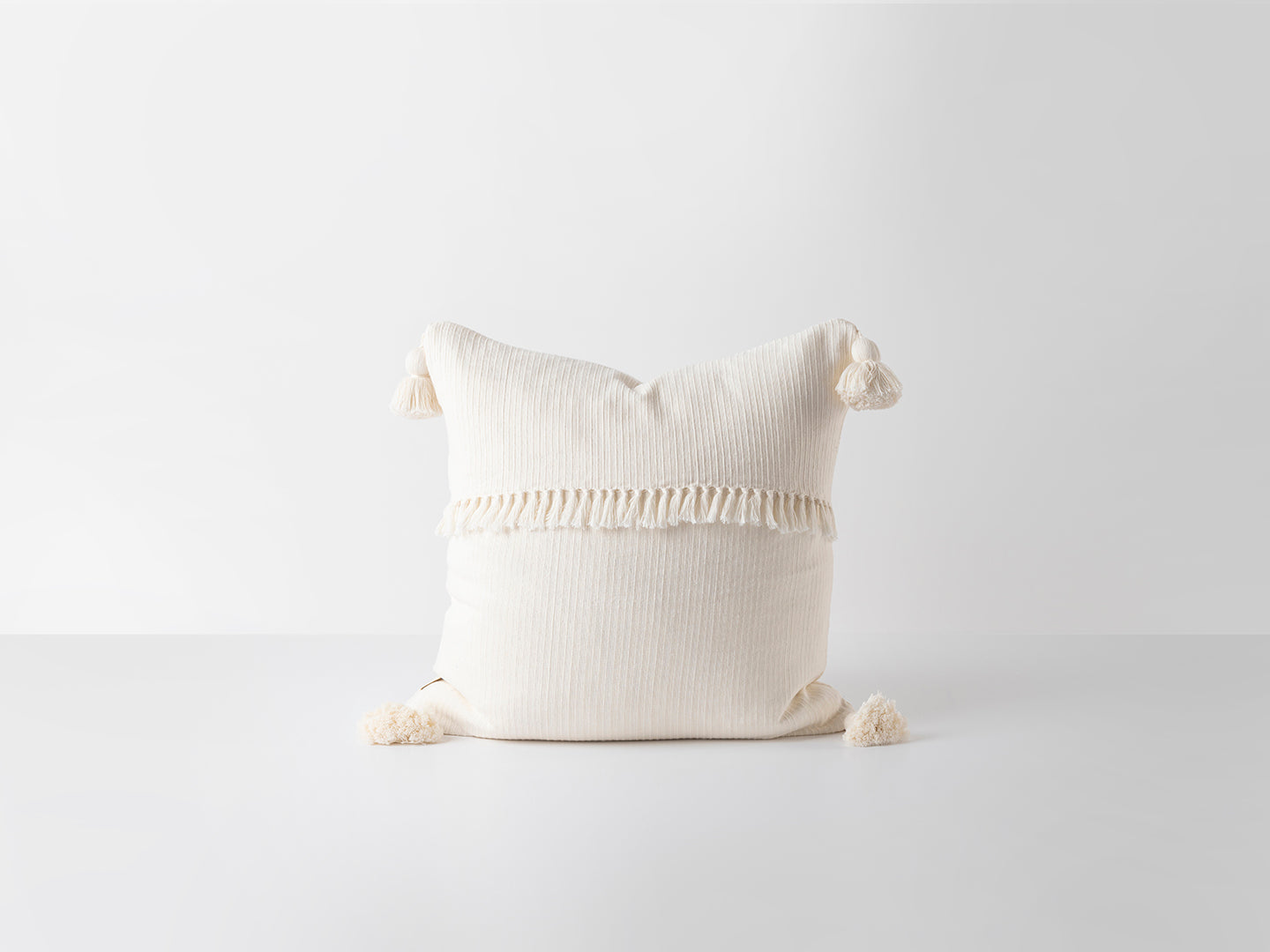 White textured pillow with decorative elements on a light gray background