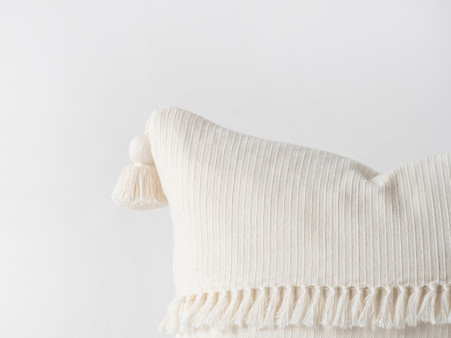 Beige pillow with tassels on a light gray background