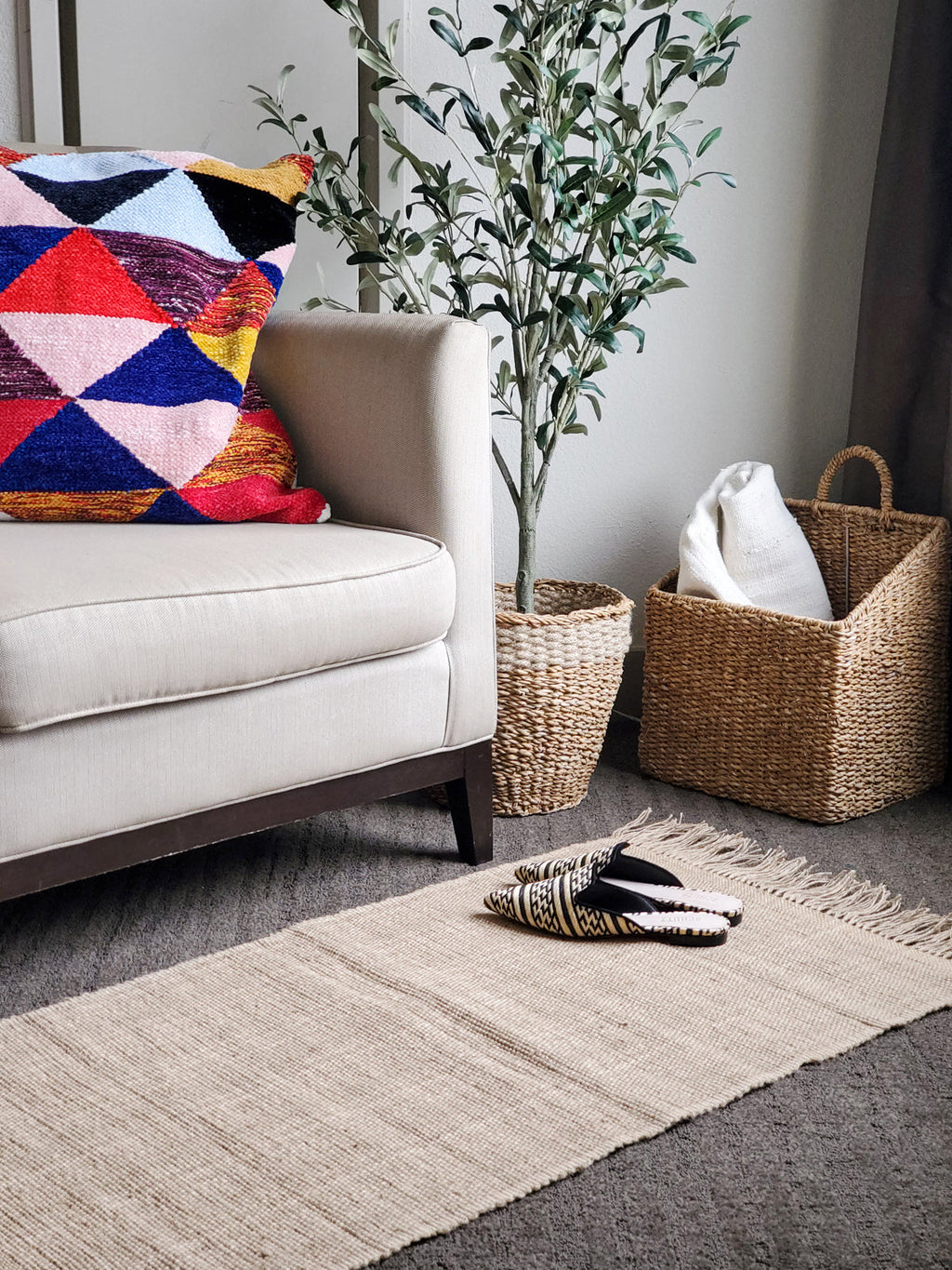Living room with a beige sofa, colorful pillow, and decorative items.
