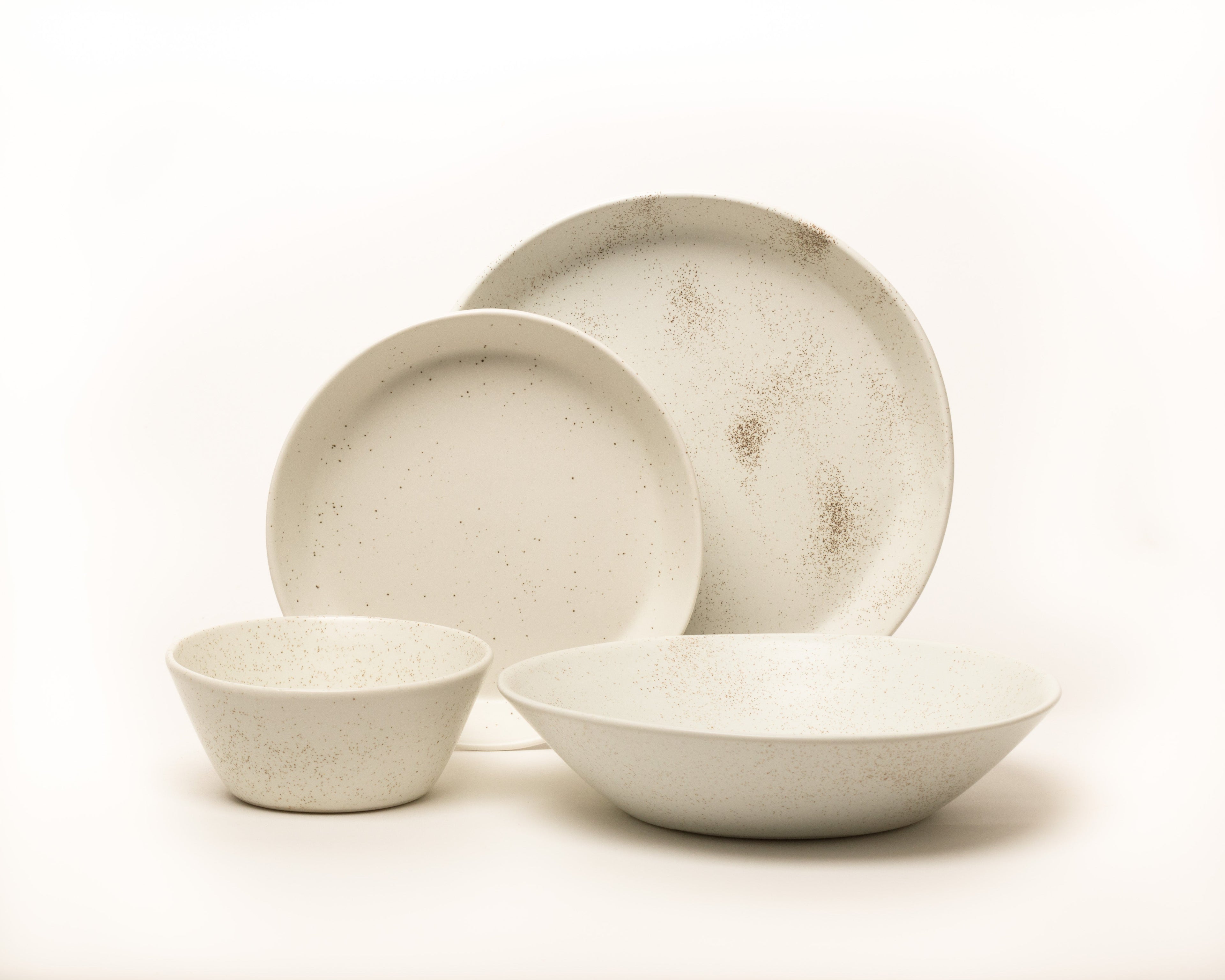 Set of ceramic bowls and plates with a speckled finish on a white background