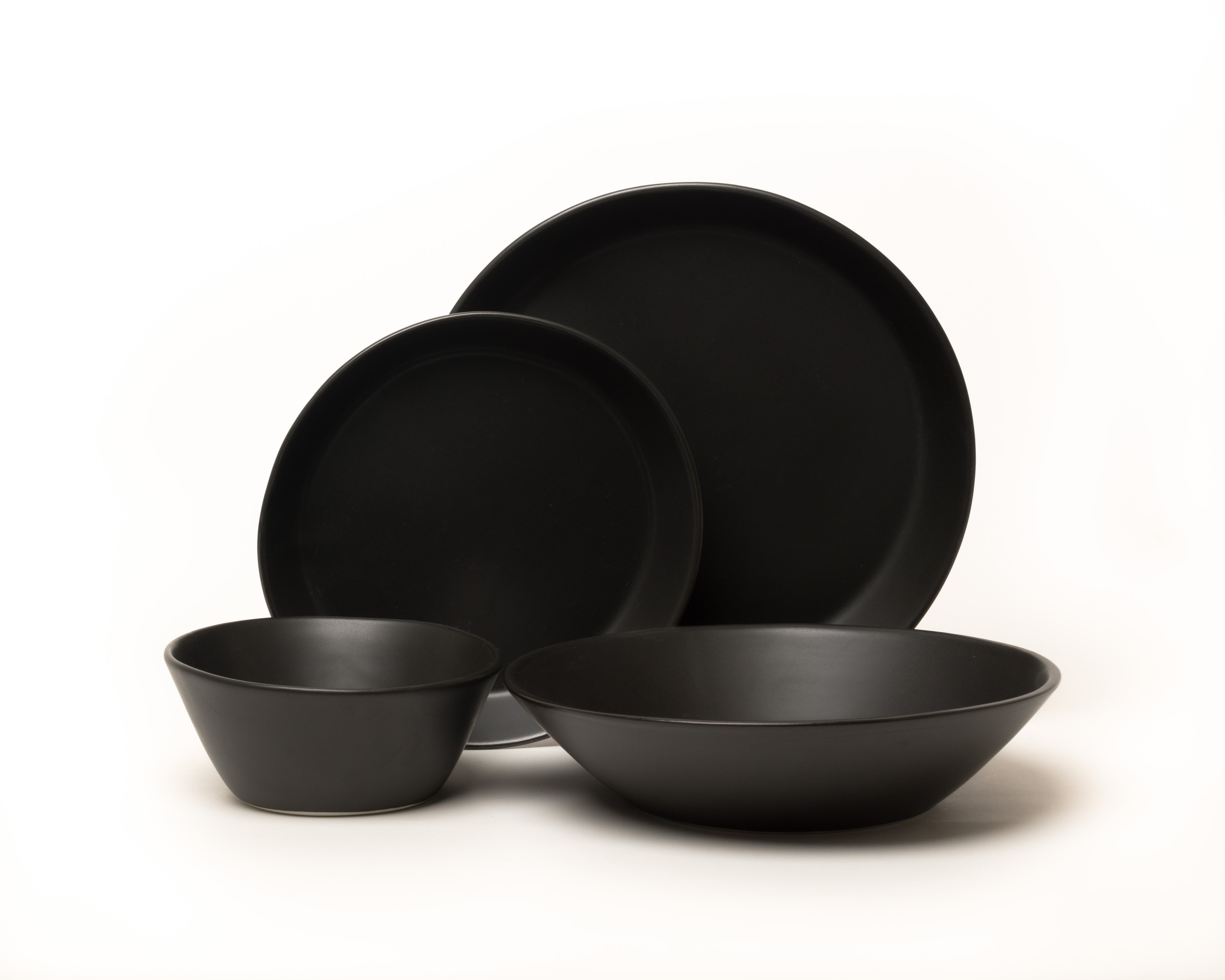 Set of black ceramic dinnerware including bowls and plates on a white background