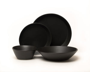 Set of black ceramic dinnerware including bowls and plates on a white background