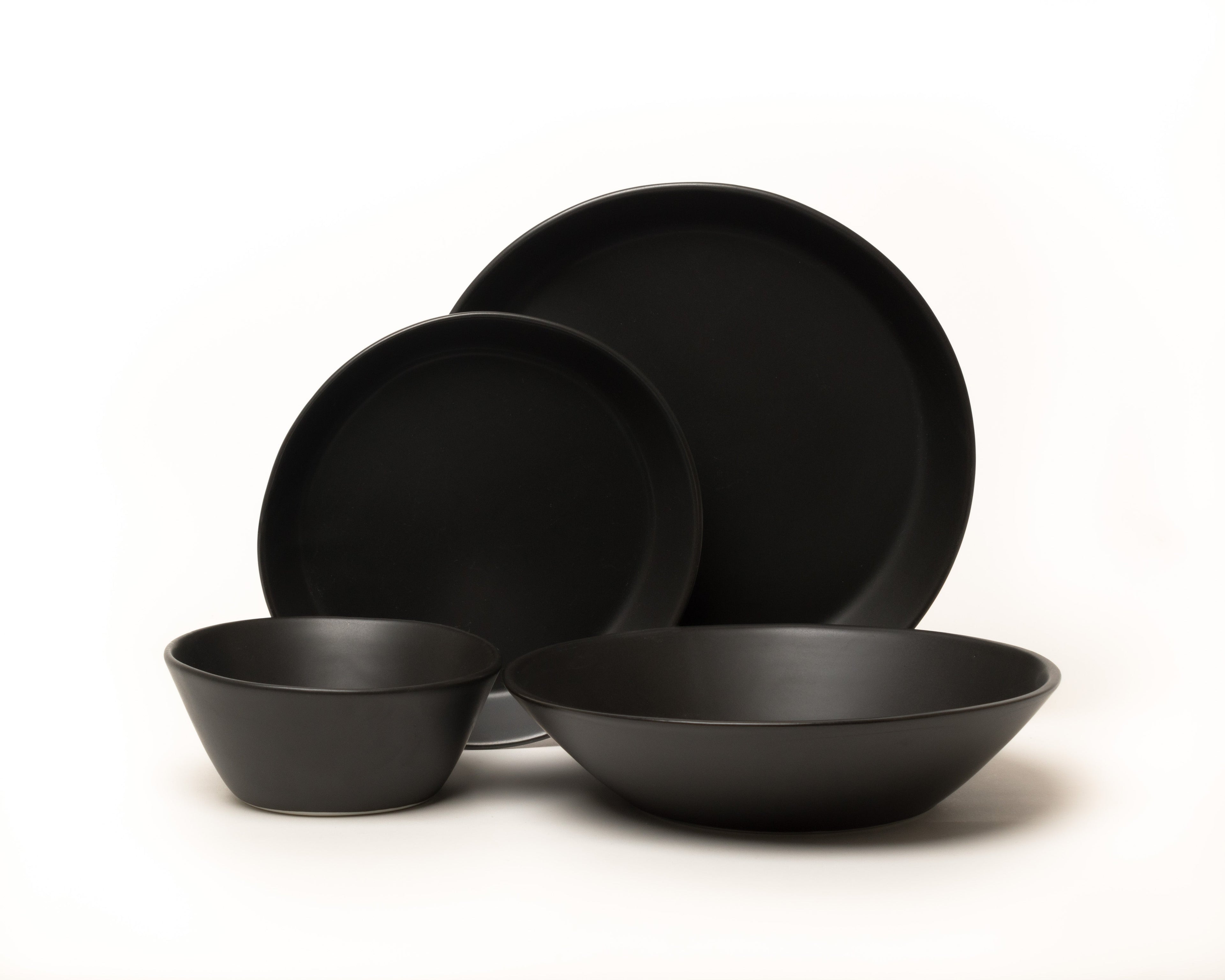 Set of black ceramic dinnerware including bowls and plates on a white background