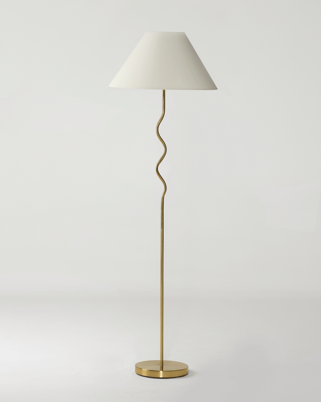 Floor lamp with a white shade and gold base on a light gray background