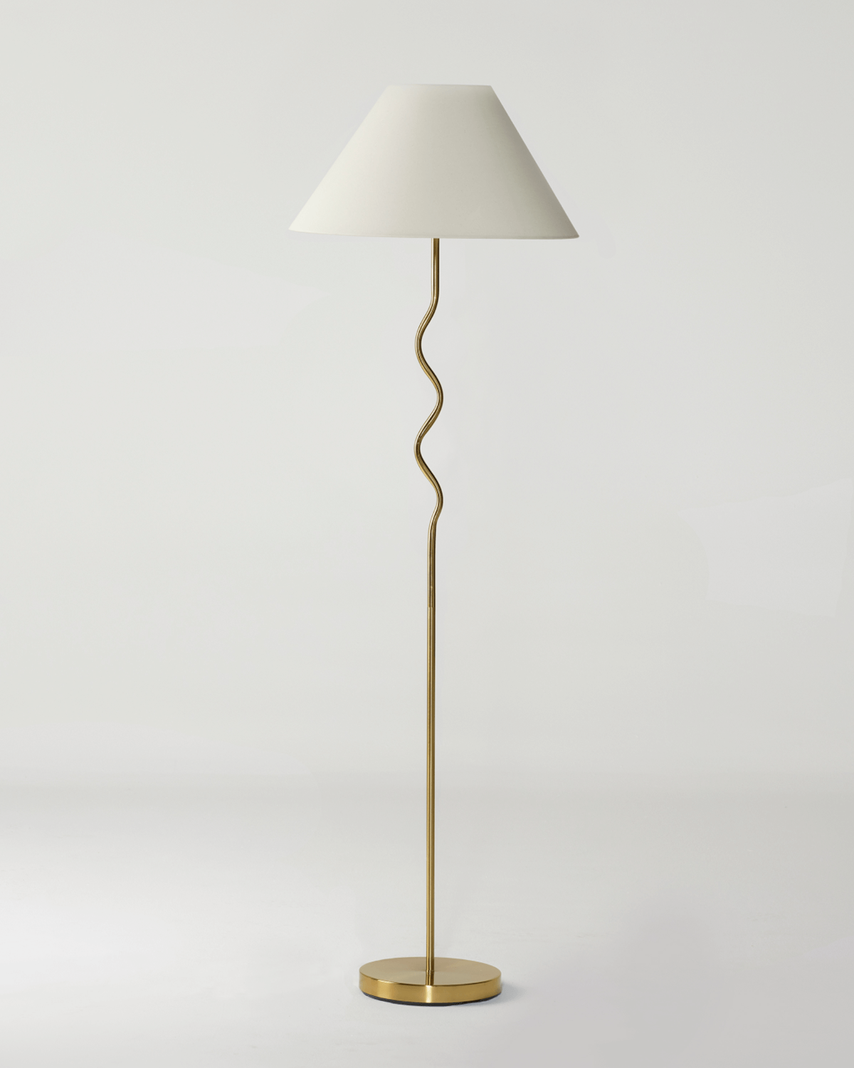 Floor lamp with a white shade and gold base on a light gray background