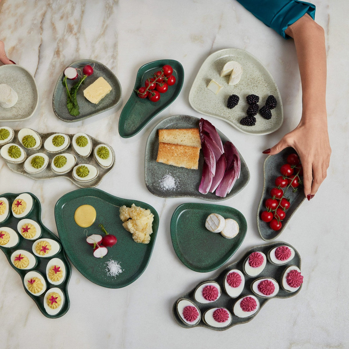 Collection of small green plates with various food items on a marble surface.