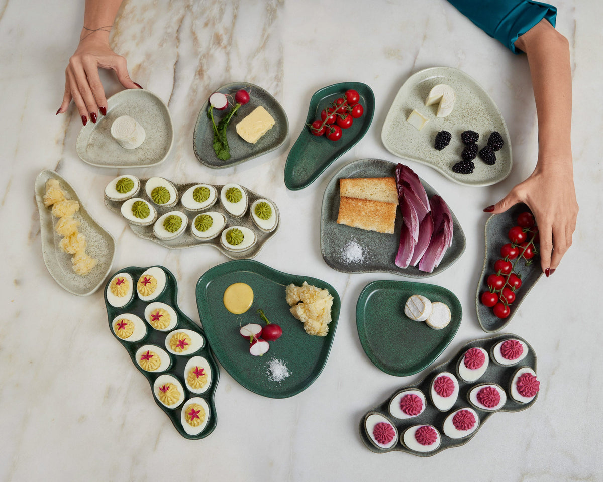 Heart-shaped ceramic plates with various food items on a marble surface.