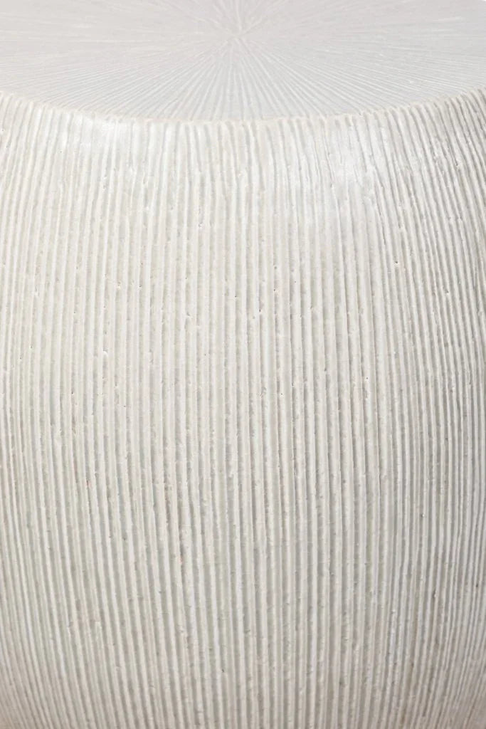 Close-up of a textured white stool on a light gray background