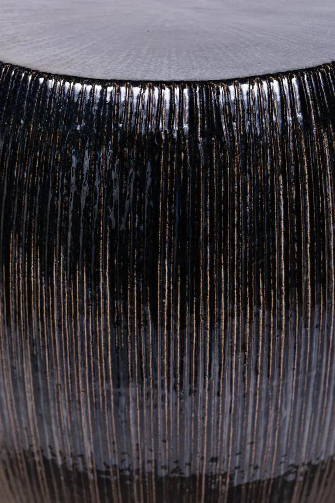 Close-up of a black fringe detail on a textured stool surface