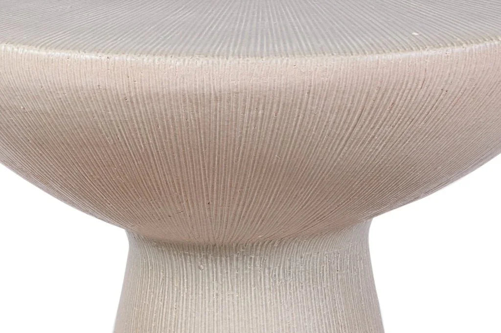 Close-up of a textured round table with a light gray top and beige base.