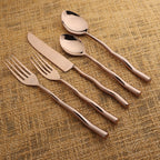 Rose gold cutlery set on a textured brown surface