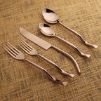 Rose gold cutlery set on a textured brown surface