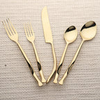 Set of gold cutlery including forks, knives, and spoons on a textured surface