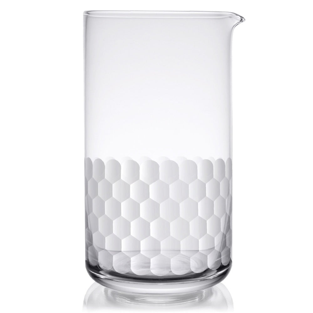 Clear cocktail mixing glass with white honeycomb pattern on a white background