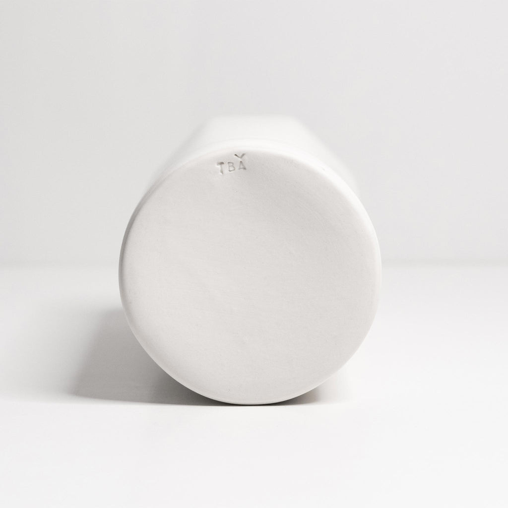 White ceramic bottom of a tubular vase on a light gray background
