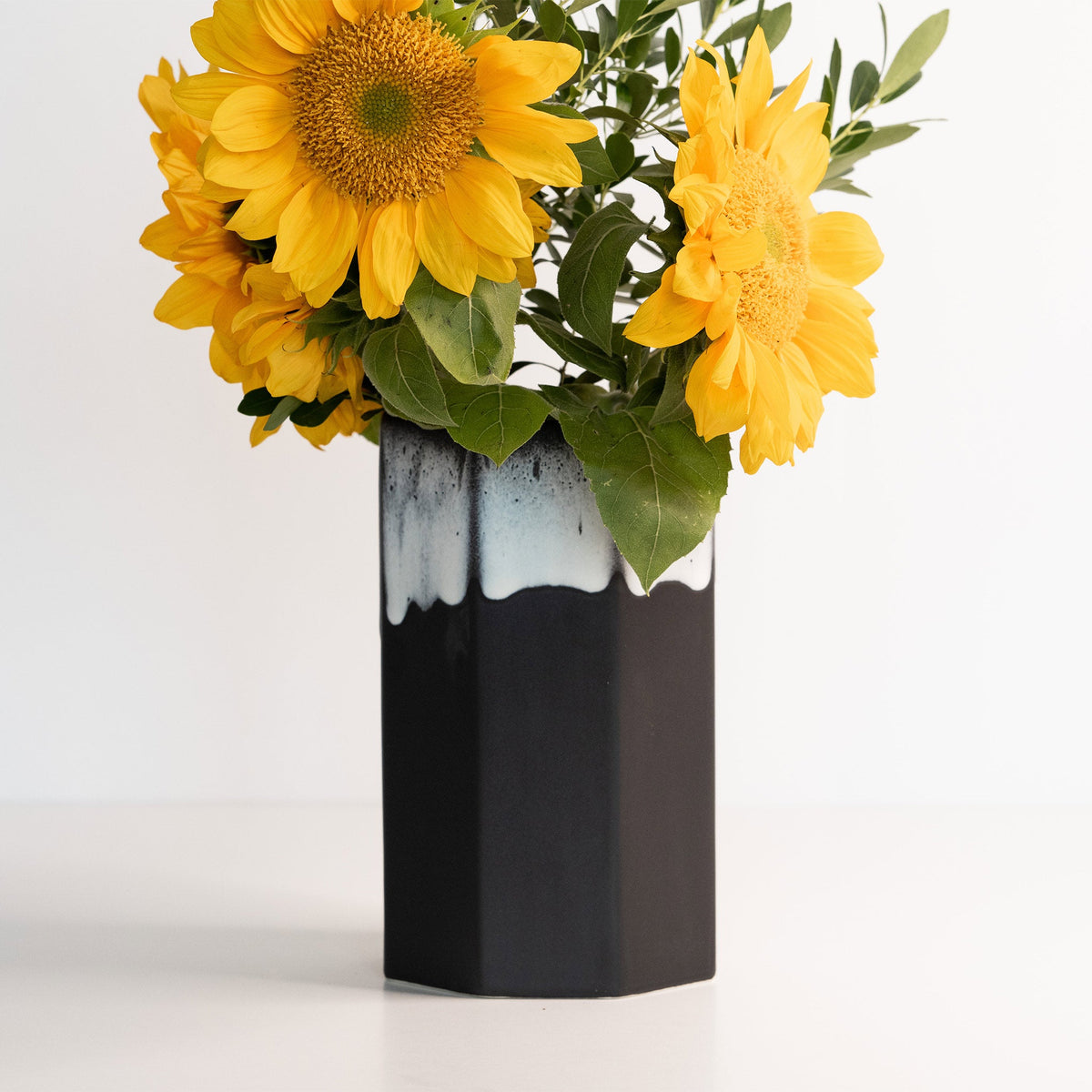 Black and white vase with yellow sunflowers on a white background