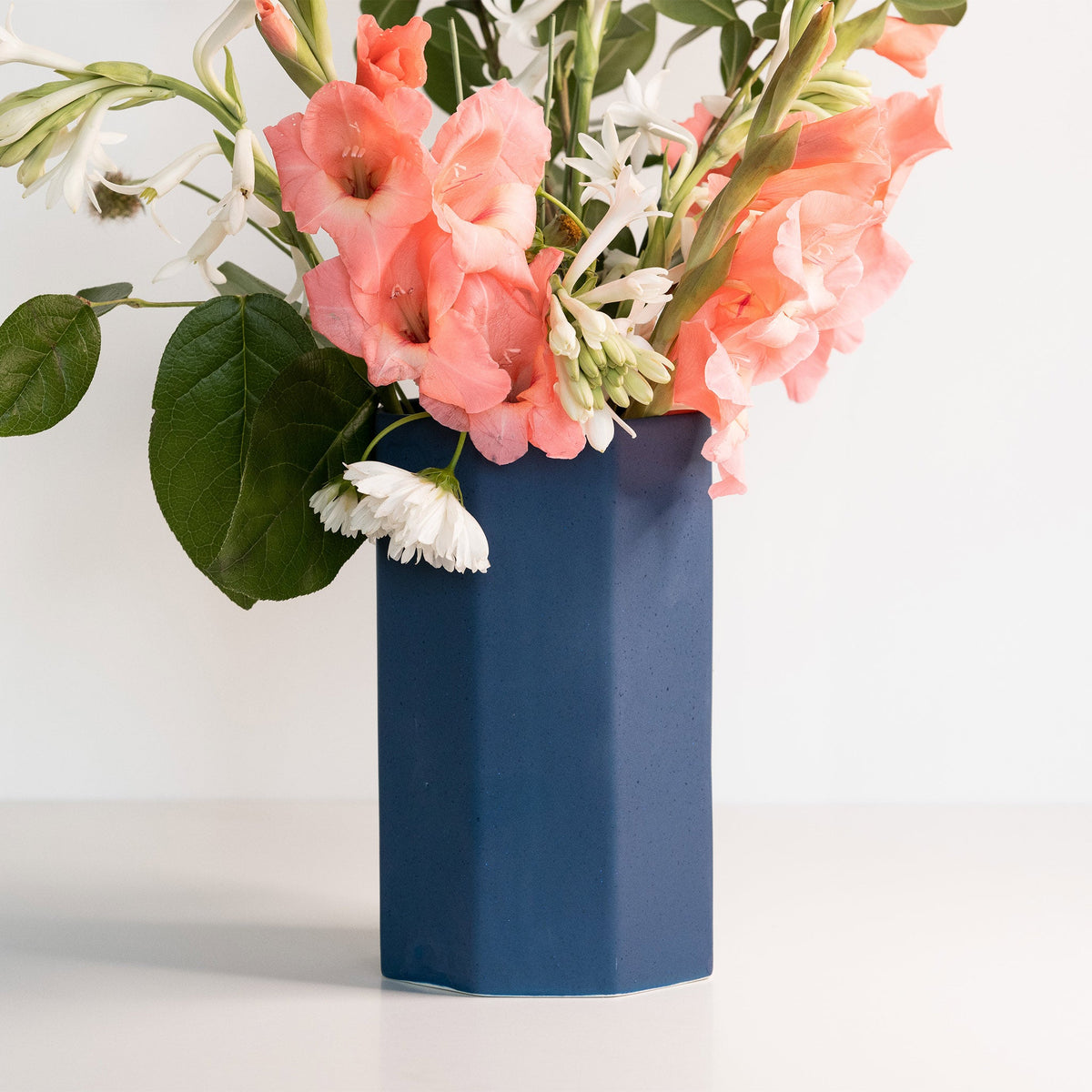Blue vase with pink and white flowers on a white background