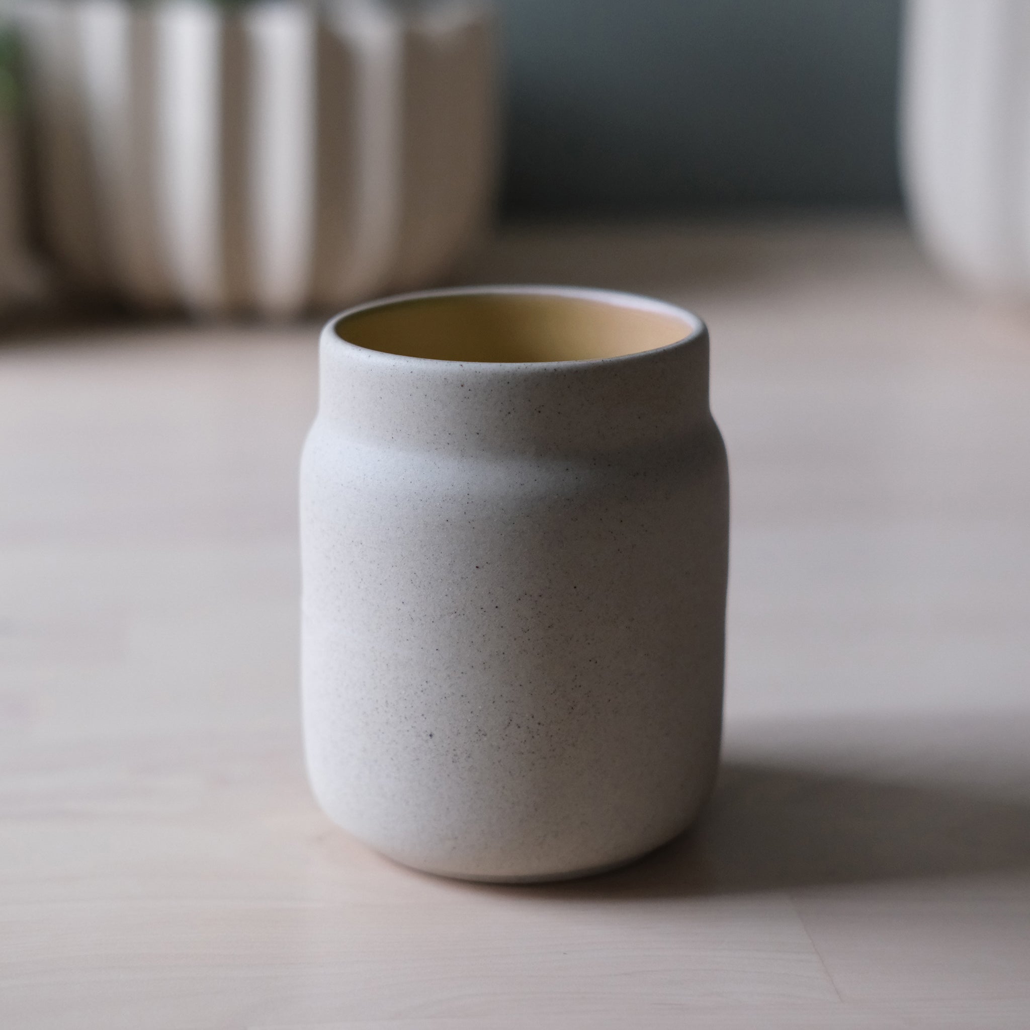 Gray ceramic vase on a light wooden surface with blurred background