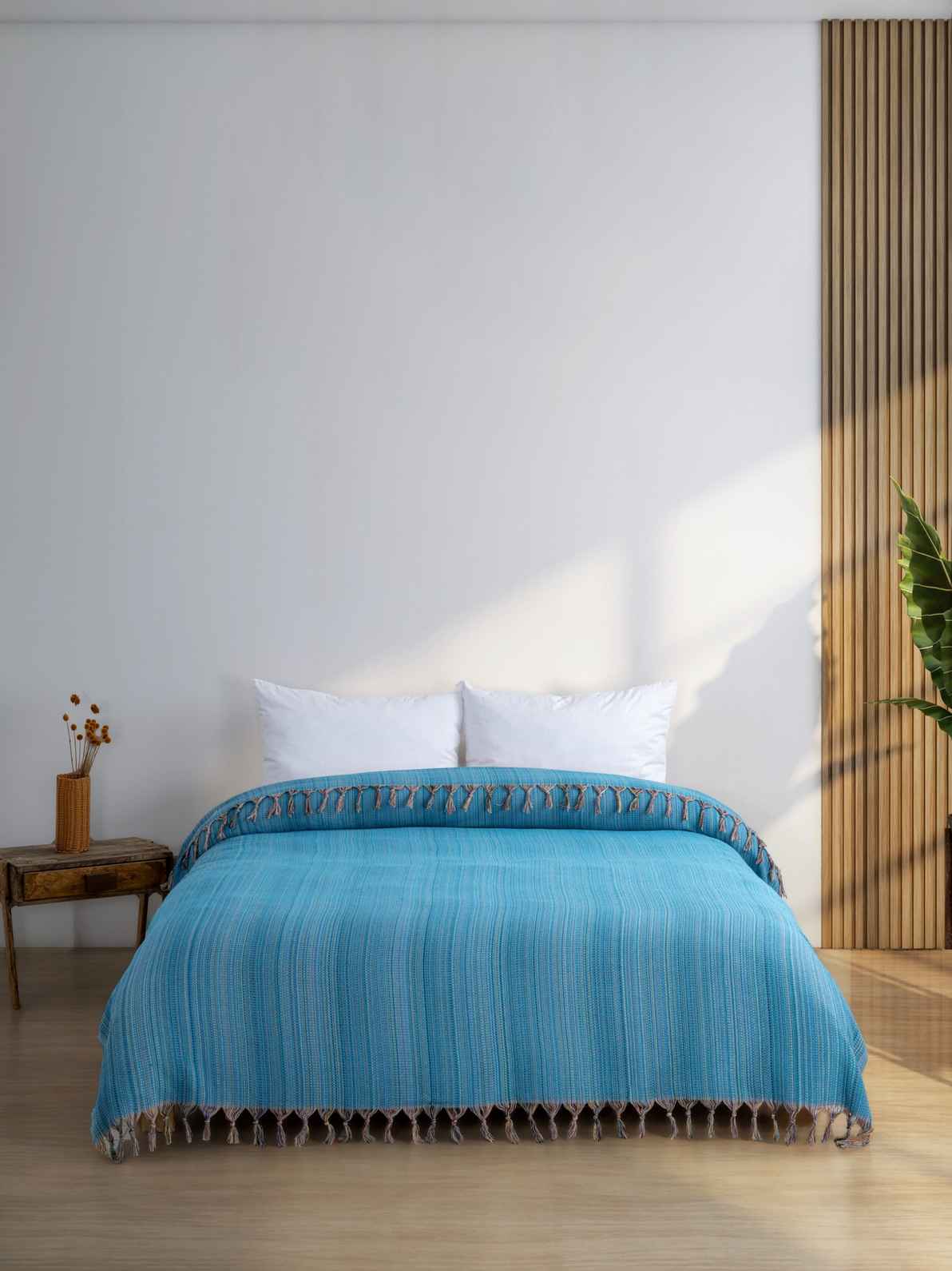 Turquoise king size blanket with fringe on neatly made bed in modern bedroom