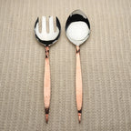 Set of silver serving spoons with rose gold handles on a white background