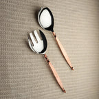 Copper-handled silverware set on a textured beige surface