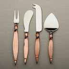 Set of four metal cheese tools with rose gold handles on a gray background