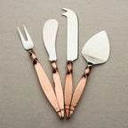 Set of four cheese tools with rose gold handles on a gray background